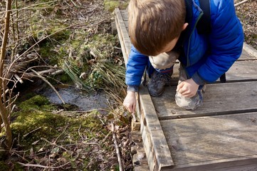 Boy making a geocache find under a boardwalk © Fergus Lang