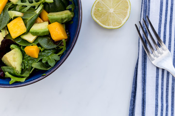 Bowl of mango avocado salad with lime and fork