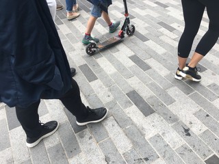 Pedestrian feet and scooter on a monotone brick path, Kingston upon Thames, Surrey