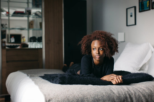 Indoor Portrait of Beautiful Black Female Model Lying on Hotel Bed