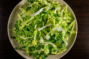 Salad with savoy cabbage and onion on wooden table
