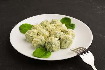 Spinacj and cheese gnocchi on white plate with fork