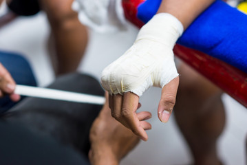 Muay Thai or Thai boxing fighter putting bandage on the hands preparing to fight