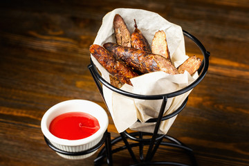 Closeup image of grilled sausages with tomato sauce at wooden board background.