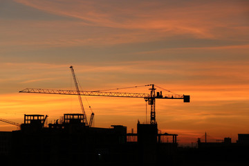Obraz premium Silhouette crane and building construction sunset background gold sky color in the evening time
