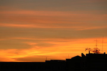 Naklejka na ściany i meble Silhouette and stanchion on roof houses sunset time sky gold color in the evening