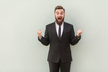 Young adult bearded business man doing a winner gesture