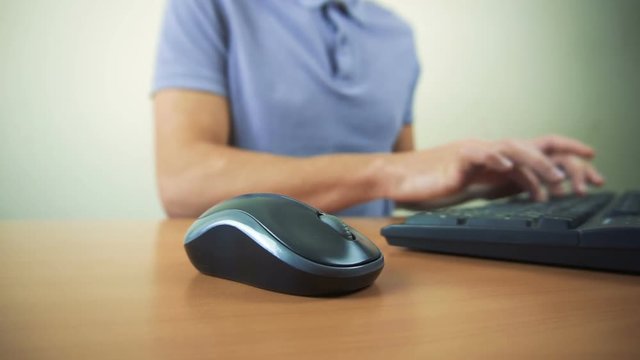 Close up of hands typing on computer keyboard and mouse