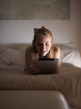 Pretty girl browsing tablet on bed