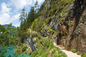 Fototapeta na wymiar Walking trail around the lake is fenced with wooden railings. Magnificent Alpine lake Lago di Braies