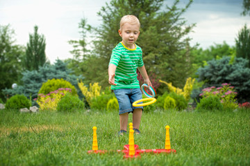  Cute boy playing a game throwing rings outdoors in summer Park