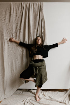 tomboy styled woman leaning back against wall with cloth hanging