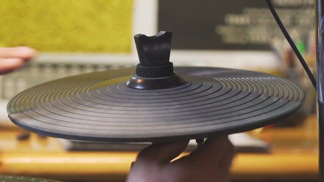 Drummer's fingers beating on an electric hi-hat cymbal.