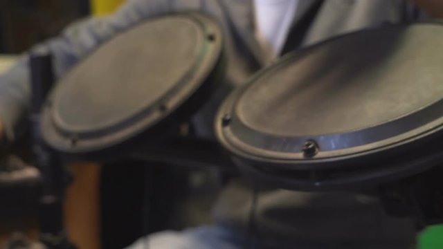Two drummers playing at the same time the same electric drums, beating their hands mainly on tom-toms and cymbals.