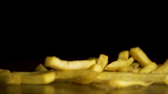 French fries fall on the table isolated on black background. Fastfood. French fries. Flying fried potatoes on black background. Pile of french fries over black background
