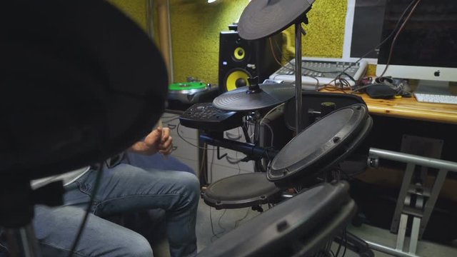 Drummer playing his electric drums, partly hidden by the crash cymbal in foregound.