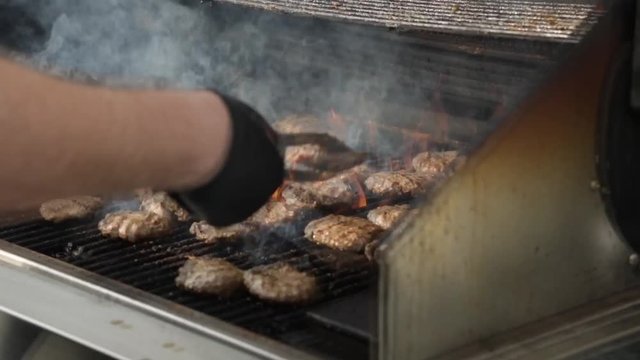 Summertime man cooking food while flipping kosher meat burgers on the grill in outdoors 