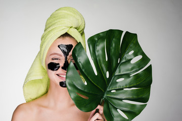 girl with a towel on her head applied a black mask to clean the problem skin of her face