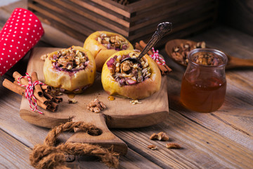 Baked apples stuffed with berries, walnuts and honey on a wooden cutting board.