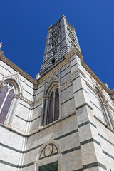 View from below of the spectacular bell tower of the Basilica of Santa Maria Assunta in Siena, Italy