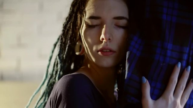 face of informal young woman with dreadlocks is hugging and kissing belly of her homosexual girlfriend