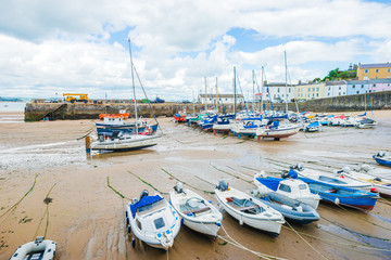 Fototapeta na wymiar Boats on the sandy beach at low tide in Tenby bay, Wales