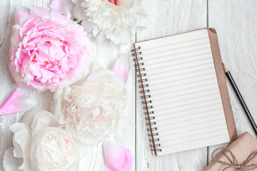 Fototapeta na wymiar pink and white peony flowers with blank lined notebook and gift box on white wooden table