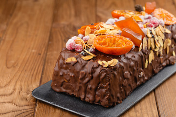 Traditional christmas fruit cake in chocolate glaze on wooden background