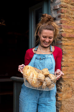 Smiling female holding basket with bread