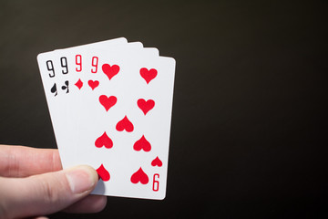 Abstract: man hand holding playing card four nine isolated on black background with copyspace poker set four nine
