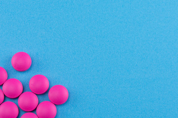 pink pills on blue background with copy space