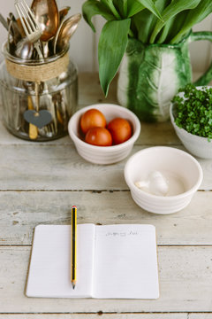 Kitchen counter, with black shopping list, spring flowers and kitchen essentials.