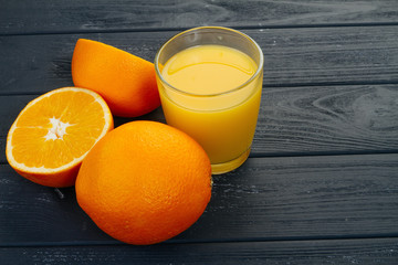 Glass of orange juice on wooden table, on wood plants background, fresh drink