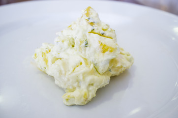 Big spoonful of American potato salad over plate