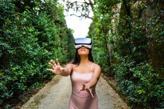 Young Woman Playing with VR Glasses in an Hedge Maze