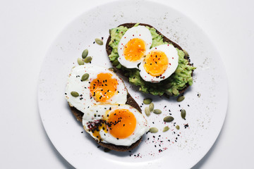 sandwich with fresh vegetables, avocado, hard-boiled eggs and pumpkin seeds with olive oil and bread. healthy diet or vegetarian food on a white background. salad with yolks on toast. top view