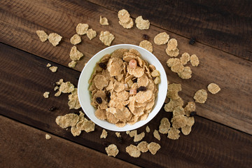 breakfast cereal ( cornflakes ) in a bowl on a wooden table background. healthy eating concept