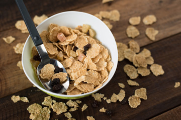 breakfast cereal ( cornflakes ) in a bowl on a wooden table background. healthy eating concept