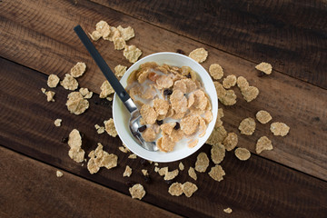 Obraz na płótnie Canvas breakfast cereal ( cornflakes ) with milk in a bowl on a wooden table background. healthy eating concept
