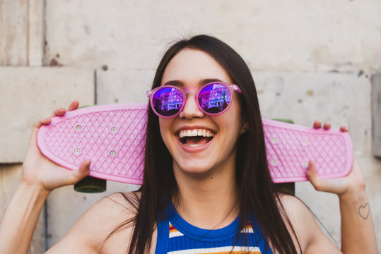 Happy woman with pink vintage skateboard and sunglasses