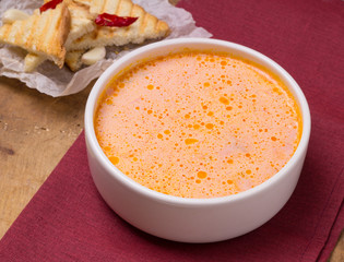 Traditional Ukrainian Russian vegetable borsch on the white bowl. Old wooden background. Sour cream sauce, red hot peppers, mini bread toast with garlic.