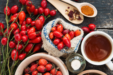 cup of herbal Dog rose tea with bunch branch Rosehips, types Rosa canina hips, essential oil. Medicinal plants and herbs composition 