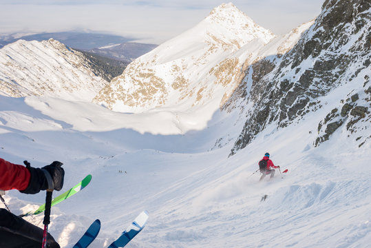 Skiers free riding on steep slope on a bright day