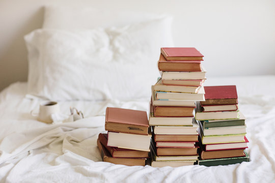 books, coffee, and glasses on an unmade bed