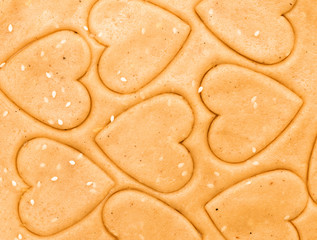 Closeup flat food background with cookie dough, cookies in form of hearts,sesam seeds 