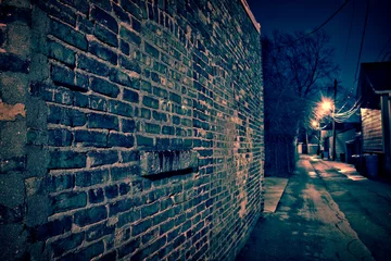 Wall murals Narrow Alley Vintage brick wall in a dark, gritty and wet Chicago alley at night after rain.