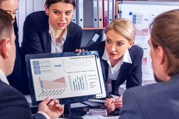 Business people office life of team people working with papers sitting table . Rivalry of men and women in team. Schemas and diagrams on computer monitor.