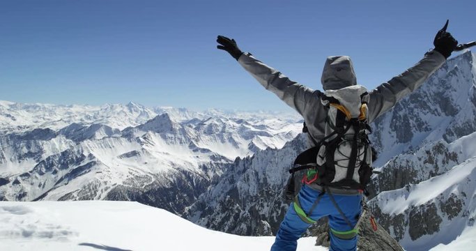 Climber mountaineer man reaching snowy mount top success in sunny day.Mountaineering ski activity. Skier people winter snow sport in alpine mountain outdoor.Back view.Slow motion 60p 4k video