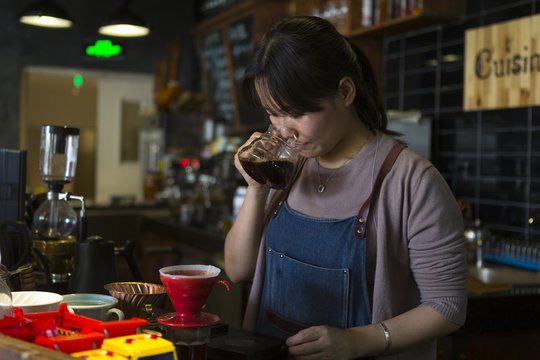 one female barista preparing coffee in cafe