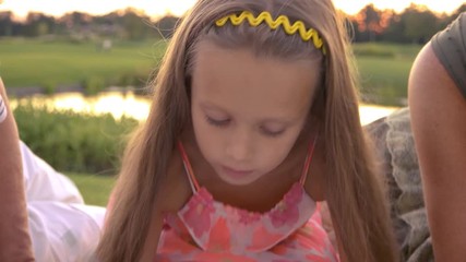 Cute little girl is drawing outdoors. Grandparents looking how their graddaughter is drawing. Importance of support and inspiration the child by seniors.